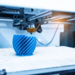 Nahaufnahme eines 3D-Druckers, welcher einen blauen Gegenstand druckt